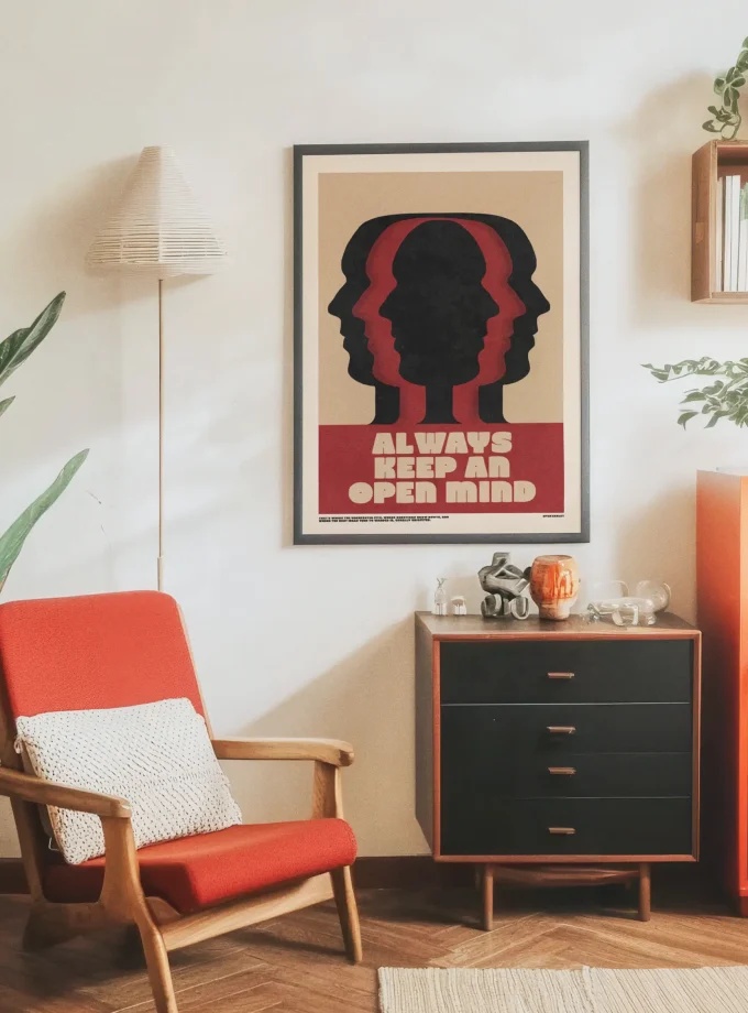 The ‘Always Keep an Open Mind’ poster by Spektaklet Studio – hanging on a living room wall with a red retro chair and wooden dresser.